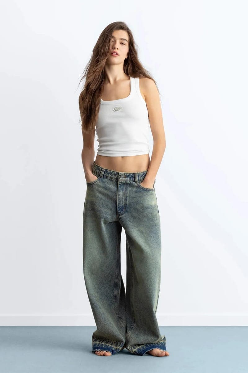 Person wearing faded wide-leg jeans and a white tank
